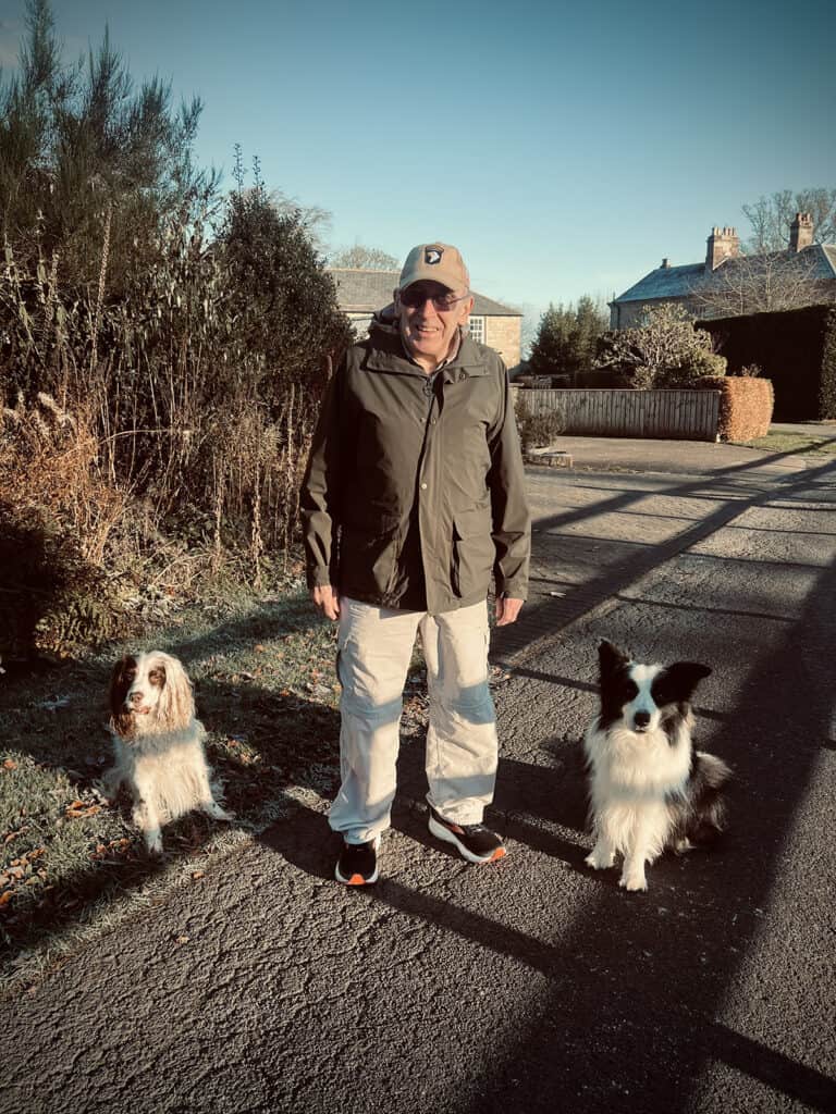 Dog owner standing with two calm dogs on a quiet village walk
